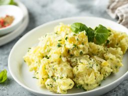 Kartoffelsalat auf einem Teller. Angerichtet mit grüner Petersilie